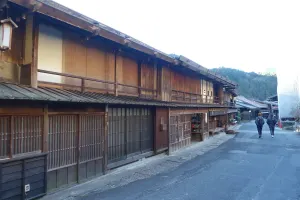 Walkers passing the dark wooden inns and shopfronts of Tsumago-juku post town on the Nakasendo